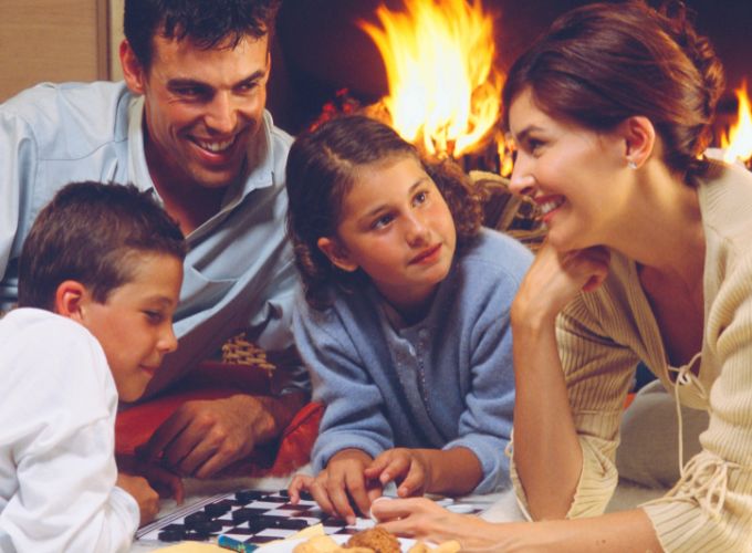A família à volta da lareira a lenha a desfrutar de jogos em família