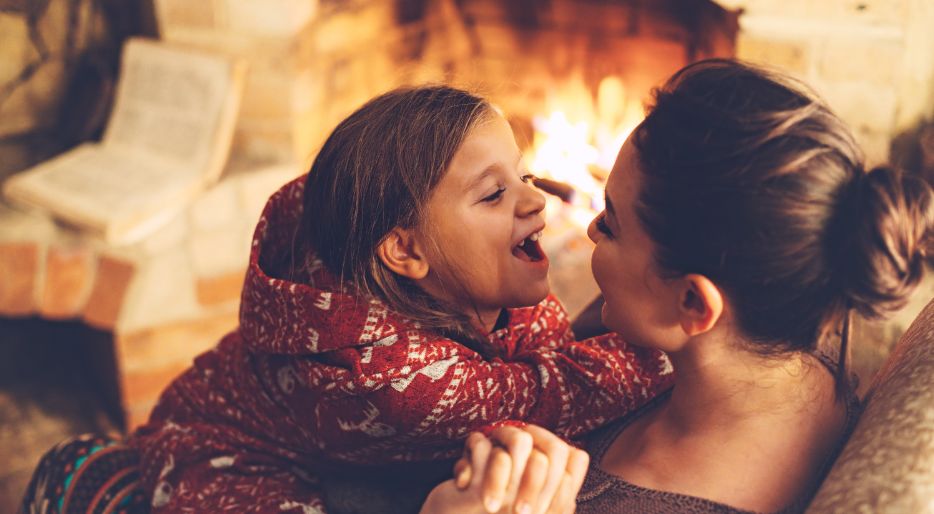 Familia alrededor de la chimenea de leña disfrutando de juegos en familia